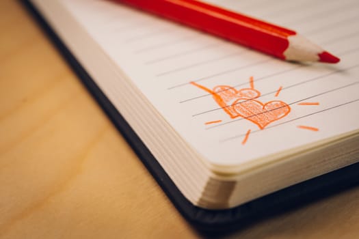 love hearts on notebook with red pen over a wooden table. Suitable for love, valentine, anniversary, couple and friendship concepts.