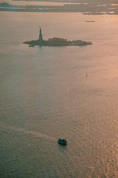 Liberty island and Statue of Liberty aerial photo at sunset or golden hour. Teal and orange style.