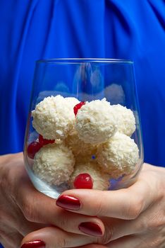 White Coconut Truffles in wine glass with mint leave. Women holding wine glass with Coconut cookies