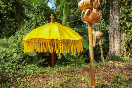 Decoration of Hindu temple complex Batukaru on Bali island in Indonesia. Yellow and white decorative umbrellas line the path for believing visitors. Colorful fabric umbrellas with decorative fringes.
