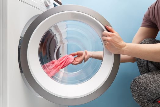 girl takes out the laundry from the washing machine. woman puts clothes in a washing machine.
