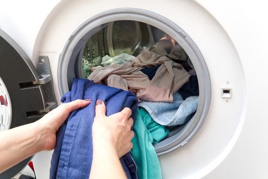 girl takes out the laundry from the washing machine. woman puts clothes in a washing machine.