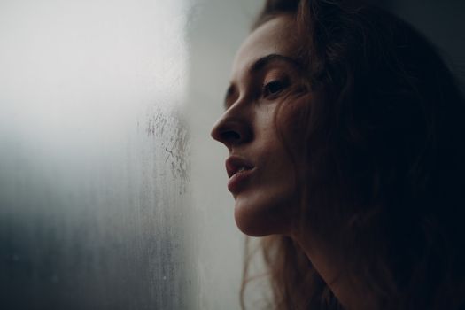 Portrait of young beautiful woman in profile near misted window