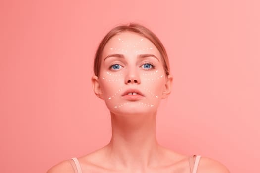 Young beautiful female close up facial portrait with arrows on her face on pink background