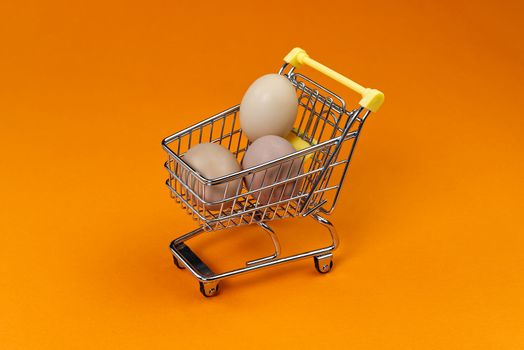 chicken eggs in a shopping cart. isolated on orange.