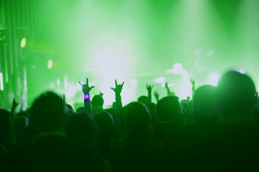 Concert, event or party concept. People with hands up at scene, spotlight, colored green light.