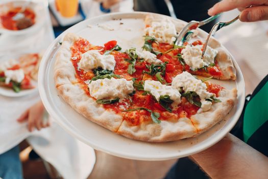 The waiter serves pizza on a dish