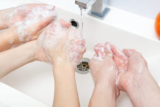 Childrens washing hands with soap under the crane with water. close-up. personal hygiene concept.