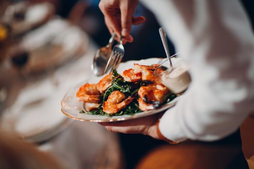 Waiter serves shrimp with arugula