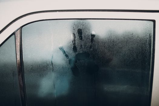 Rain and handprint on glass of car