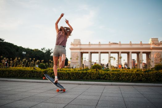 Young sporty woman riding on the longboard in the park