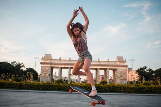 Young sporty woman riding on the longboard in the park