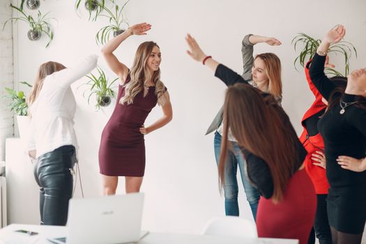 Team women doing exercises in office. Exercising females at work. Benefits of fitness for employees and managers.