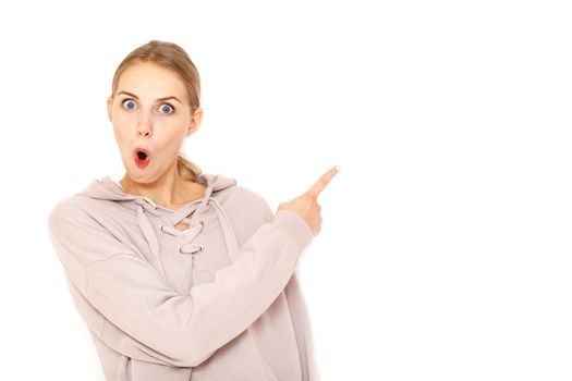 Young amazed woman pointing finger to copy space white background