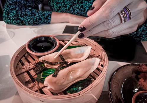 Woman hand holding japaneese gyoza with chopsticks. Japanese or asian restaurant and food