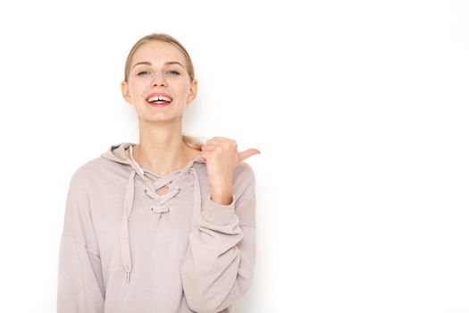 Young laughing woman pointing finger to copy space white background