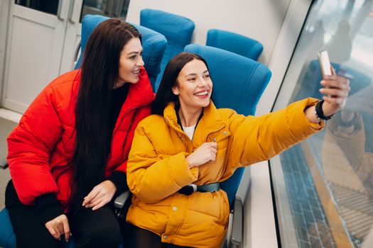 Two young women take a selfy shot with mobile phone in train