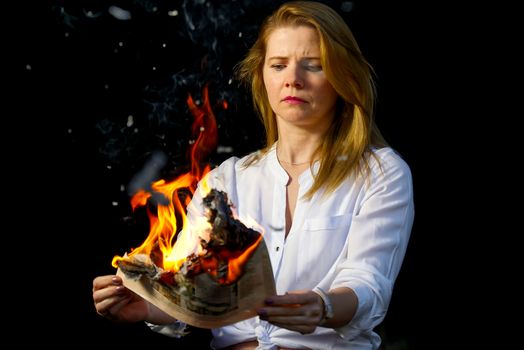 woman holding burning newspaper. Burning magazine in woman hands. fake news, breaking news concept.