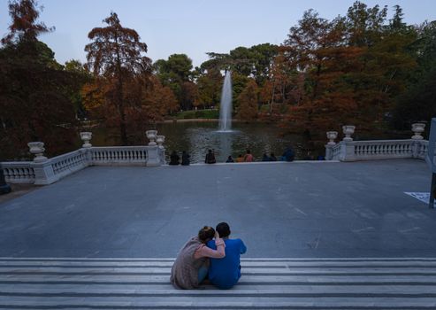 Romantic Young couple sitting together and looking to the garden pond in Parque del Retiro or Retiro Park in Madrid, Spain.