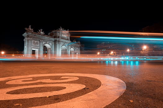 Night view of Puerta de Alcala with traffic lights in Madrid, Spain. Copy space available and 30 km per hour urban limit sign. Spain has offered to host COP25 or United Nations Climate Change Conference in Madrid