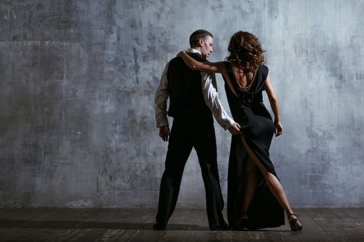 Young pretty woman in black dress and man dance tango