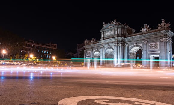 Night view of Puerta de Alcala with traffic lights in Madrid, Spain. Copy space available and 30 km per hour urban limit sign.