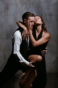 Young pretty woman in black dress and man dance tango