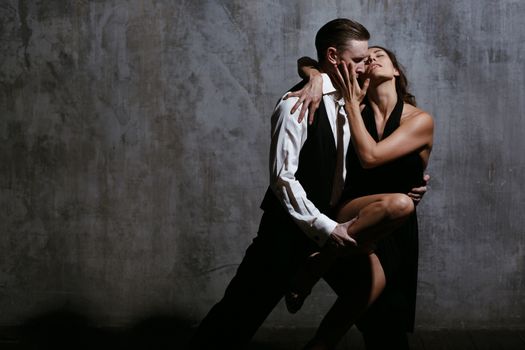 Young pretty woman in black dress and man dance tango