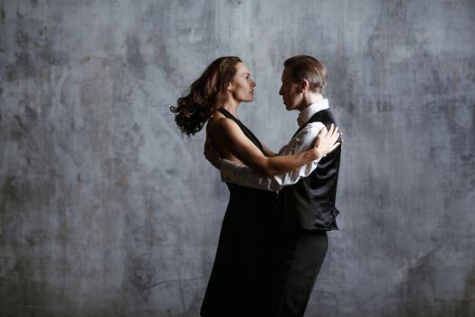 Young pretty woman in black dress and man dance tango