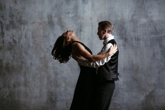 Young pretty woman in black dress and man dance tango