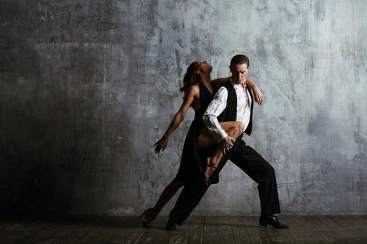 Young pretty woman in black dress and man dance tango