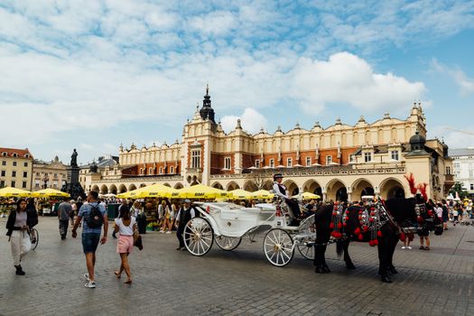 Krakow, Poland - August 15th, 2018: Traditional horse carriage waiting for passengers in front of the Cloth Hall on Krakow's main market square.