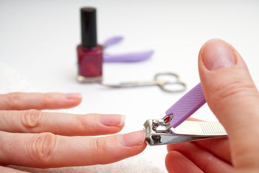 Woman Clipping Nail s with Forceps. Female cuts his nails on a white background with tweezers for nails. manicure procedures yourself at home.