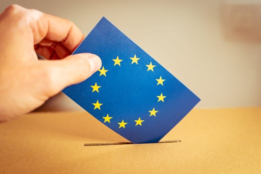 Election in European Union - voting at the ballot box. A hand putting an EU flag vote in the ballot box.