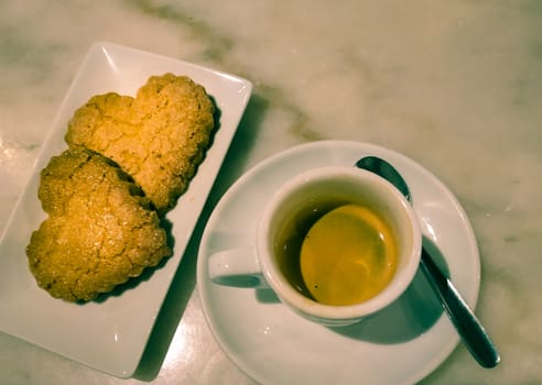 Heart cookies with cup of coffee top view in a real coffee shop. Suitable for valentine's day, couple romance, weddings, and love concepts. Copy space available