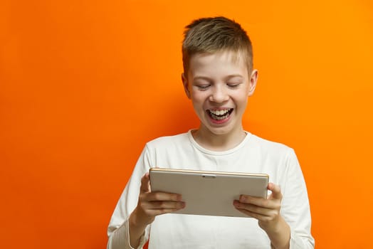 Social distancing and Online communication concept, Happy boy Chatting with friend by tablet on orange wall background. Happiness in distancing concept
