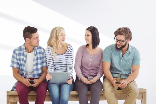 Smiling business people holding electronic gadgets while sitting on desk  against grey vignette