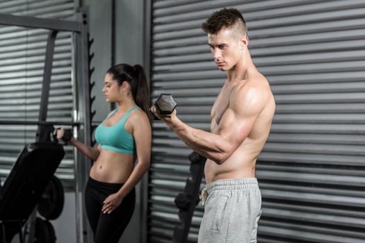 Fit people lifting dumbbells at crossfit gym