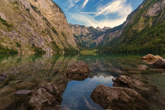 Panoramic view traditional old wooden boat house at scenic Lake Obersee on a beautiful day with foggy clouds in autumn, Bavaria, Germany