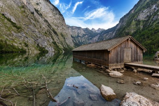 Beautiful view of traditional wooden boat house at the shores of famous Lake Obersee in scenic Nationalpark Berchtesgadener Land on a sunny day in summer, Bavaria, Germany