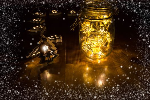 Christmas lights in a jar on the wooden table with snow frame