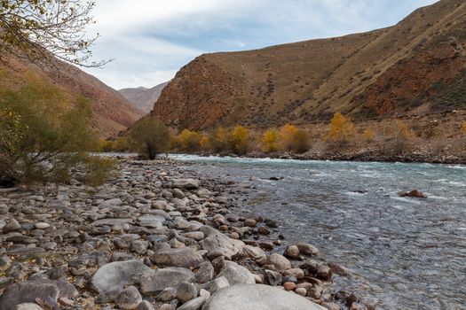 The rocky shore of a mountain river. Kokemeren river, mountain river in the Naryn region of Kyrgyzstan.