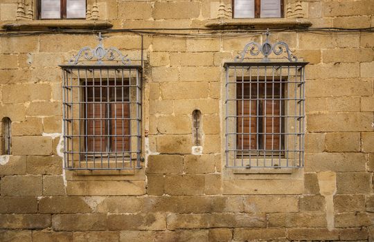 Window with bars on a stone facade in Casa del Doctor Trujillo, and old medieval palase in Plasencia, Esxtremadura, Spain.