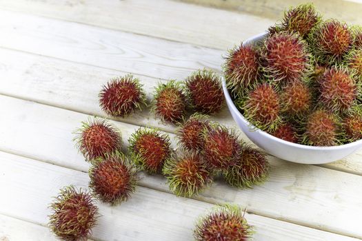 fresh rambutan in white blow and some drop on wood table.