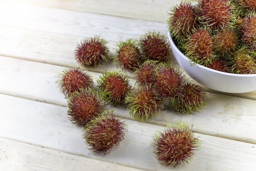 fresh rambutan in white blow and some drop on wood table.