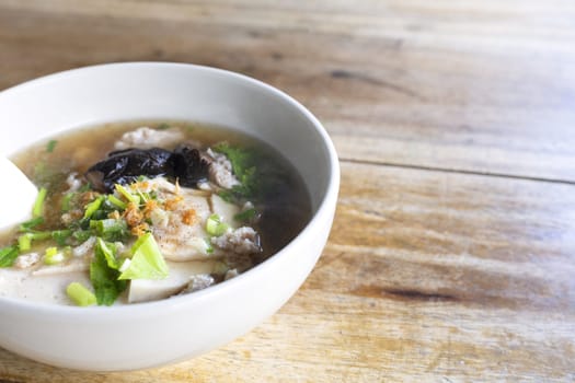 Soup with pock, pock stick, mushroom, vegetable in white bowl on wood table. with copy space for text or design