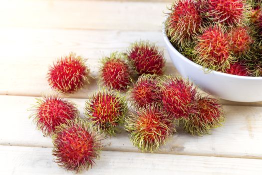 fresh rambutan in white blow and some drop on wood table. 