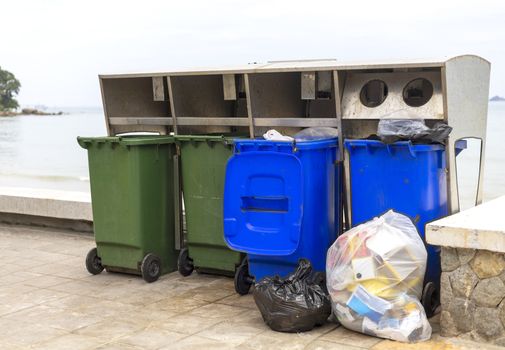 Green and blue bin for different collection Of Recycle Materials on  footpath near beach