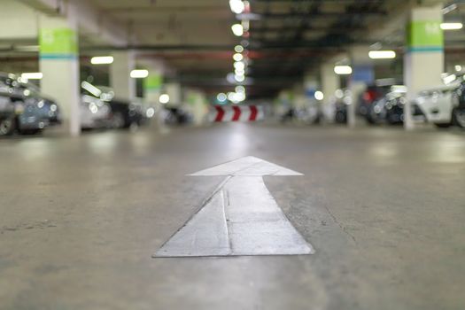 Underground parking at supermarket with white arrow sign for exit way. abstract blur image carpark bakcground.