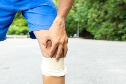 Man with blue runing shorts use hands hold on his knee after run